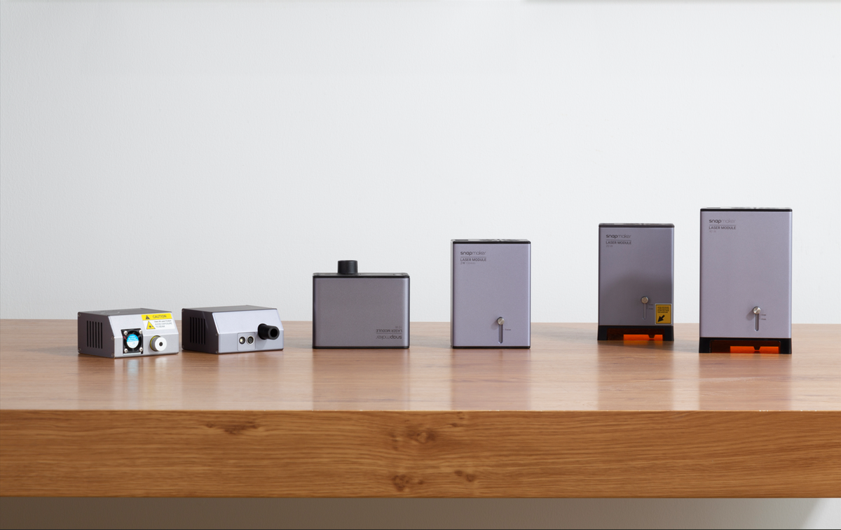 A lineup of six different Snapmaker laser modules arranged on a wooden table.