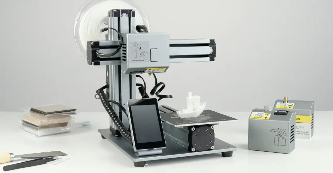 Modular desktop 3D printer with filament spool and accessory modules on a white workbench - modern additive manufacturing machine.